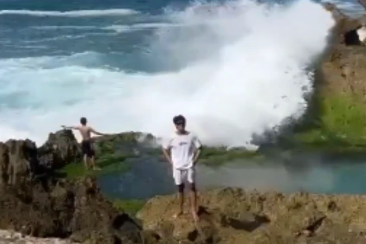 Tangkap layar video detik-detik wisatawan pantai Kedung Tumpang di Tulungagung terseret ombak besar di tebing