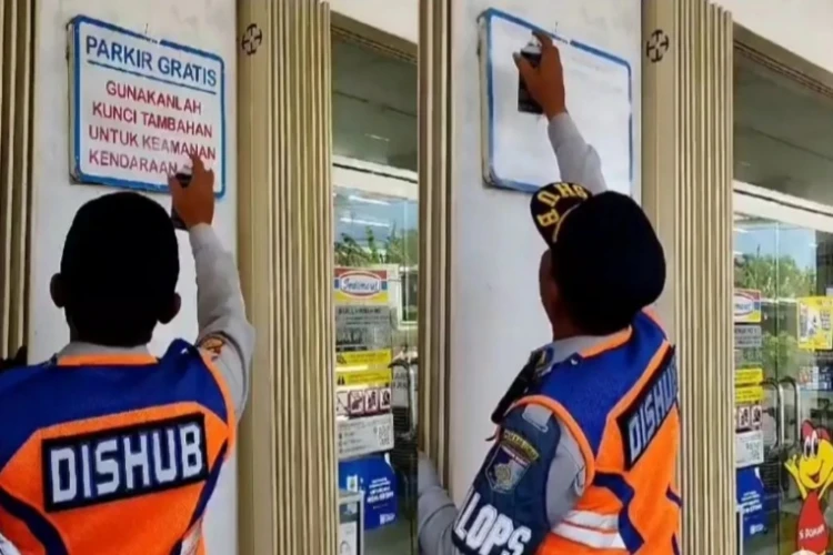 Viral aksi petugas Dishub yang menghapus tulisan parkir gratis di depan minimarket.