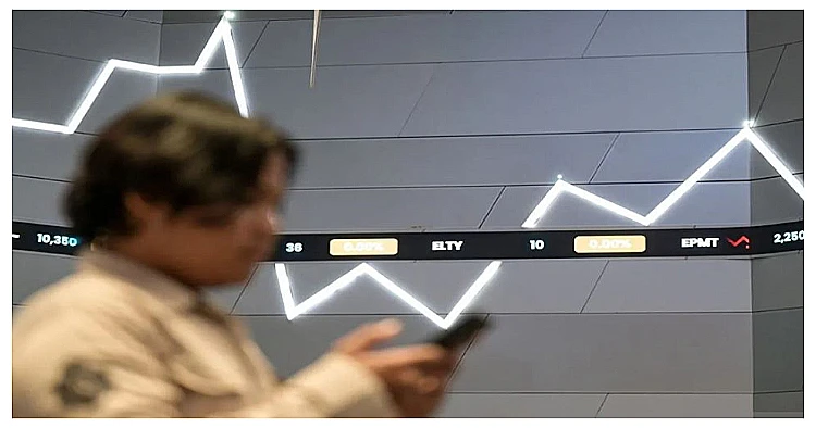 Seorang pengunjung melintas di depan layar digital yang menayangkan grafik pergerakan Indeks Harga Saham Gabungan (IHSG).