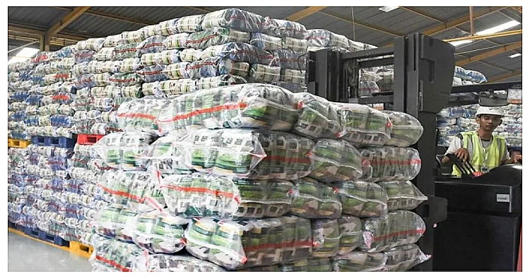 Seorang operator mengoperasikan alat berat untuk memindahkan tumpukan beras yang siap dikirim dari Gudang RPC milik Food Station