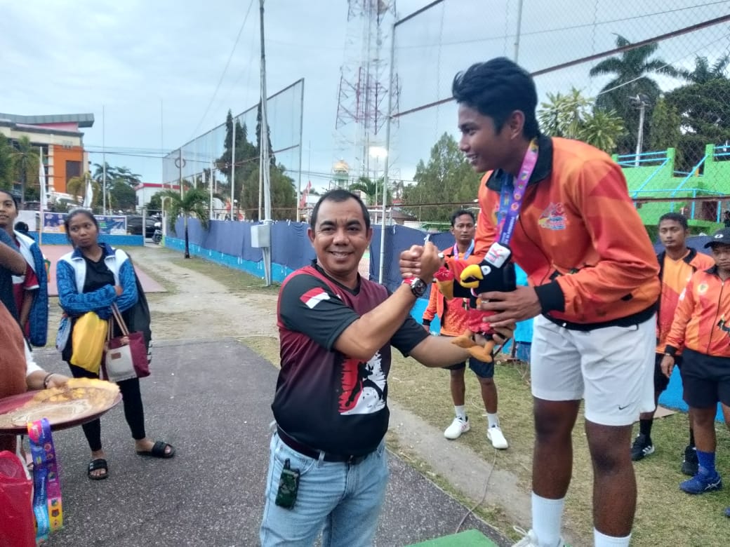 <p>FOTO; Ketua Umum KONI Parimo, Faisan Badja menyerahkan medali emas kepada petenis Parimo di lapangan tenis Gelora Luwuk, Rabu (14/12/2022). F-HUMAS KONI PARIMO.</p>

